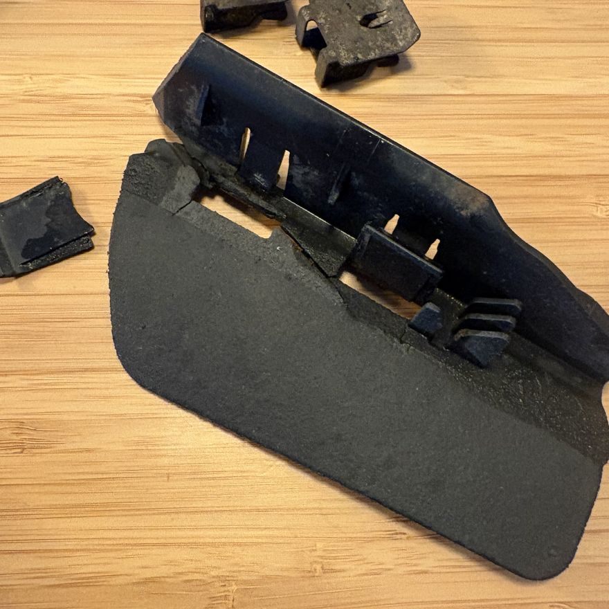 The original deflector removed and laid out on a bench in pieces, with its broken metal clips separated