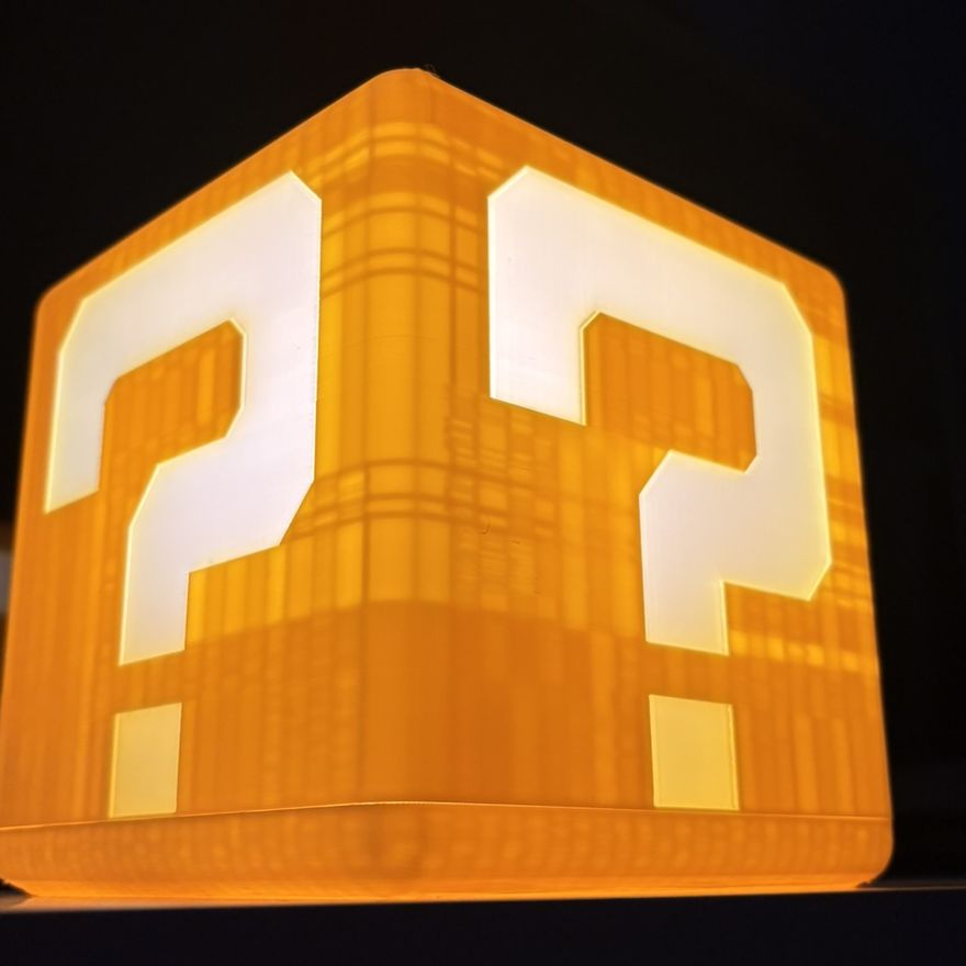 The finished question block lamp glowing warm orange in a dark room